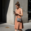 Woman in neutral minimalistic dress walking city sidewalk